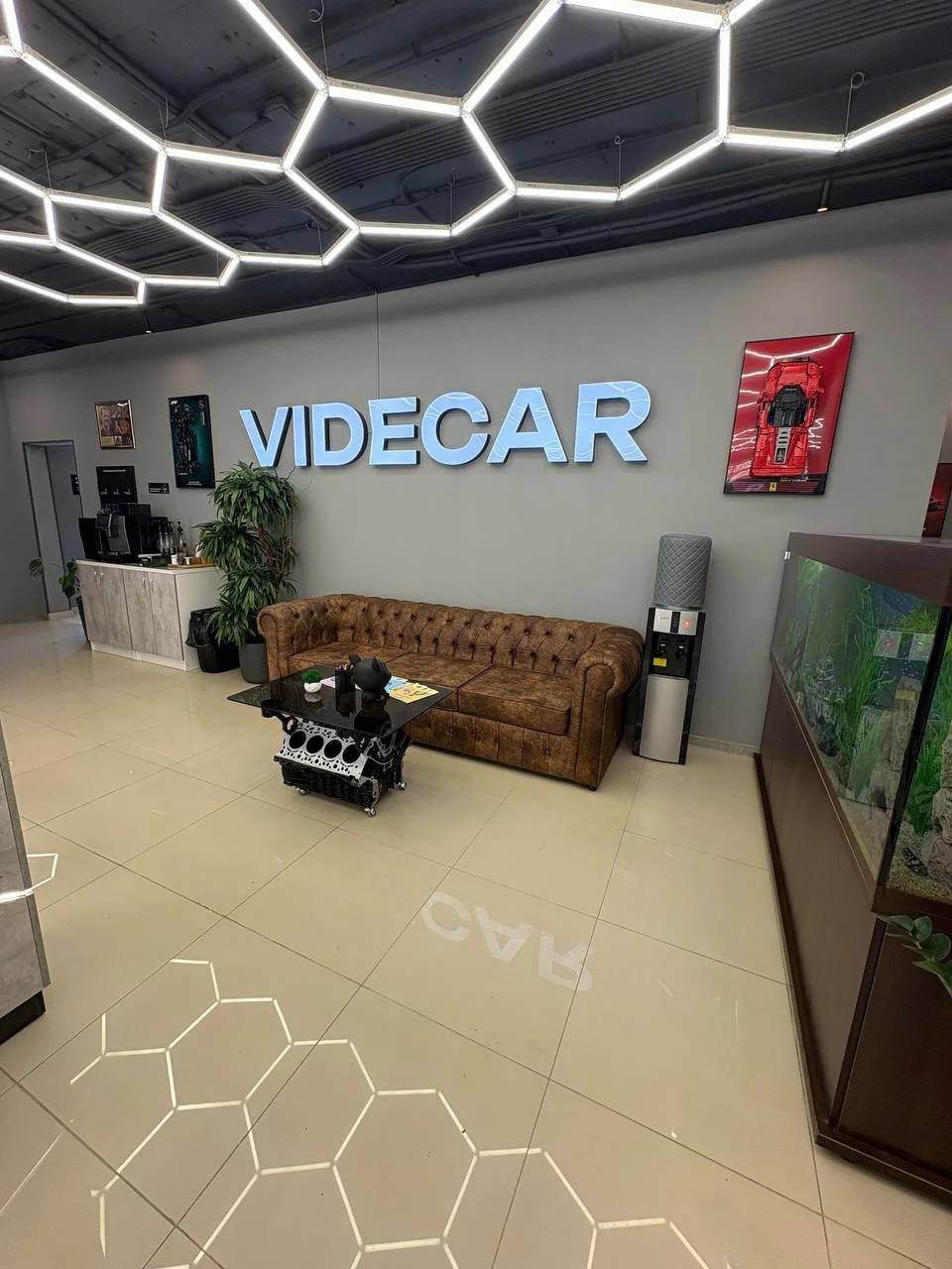 Зона ожидания в офисе: диван и логотип VIDECAR на стене